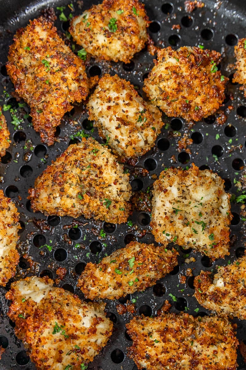 Overhead view of chicken nuggets in an air fryer basket.