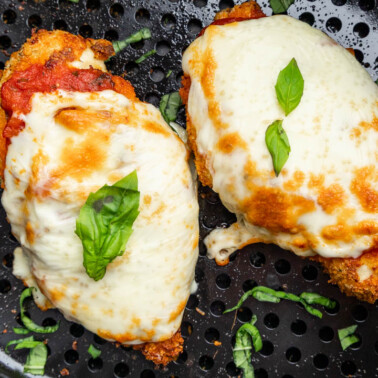 Overhead view looking into an air fryer basket with chicken parmesan.