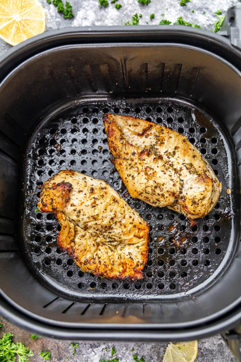Overhead view looking into an air fryer basket with chicken breasts.