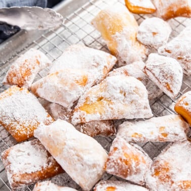 A pile of beignets on a baking sheet.
