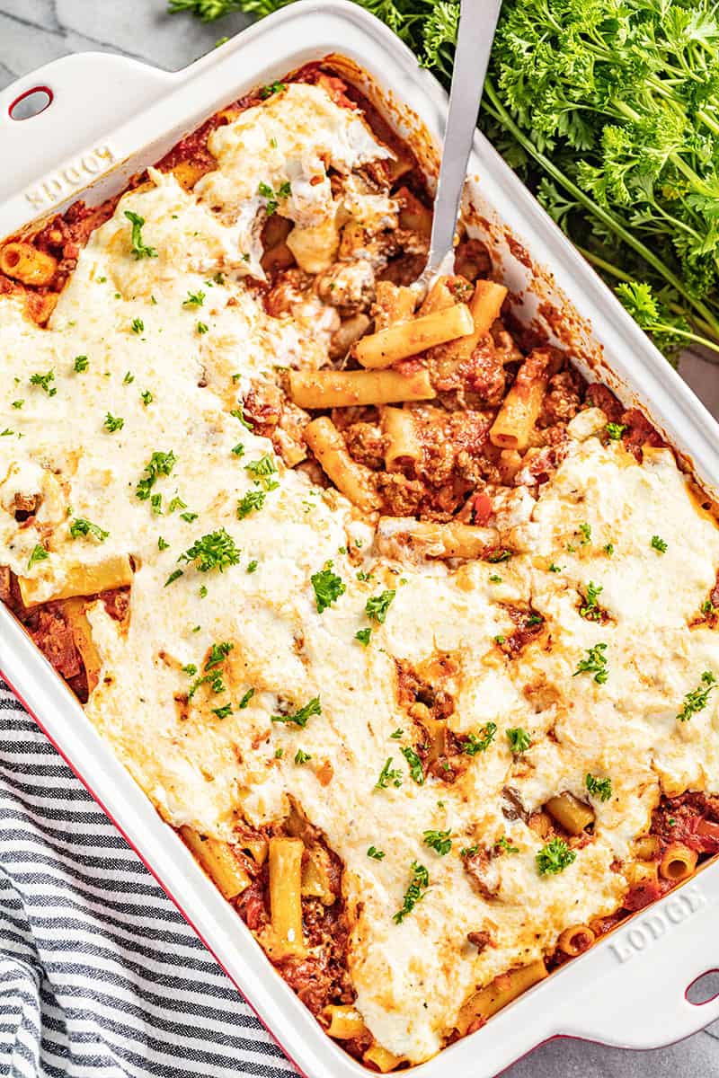 Baked ziti in a white deep baking dish with a spoon