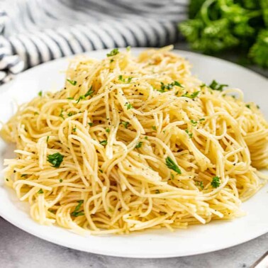 Brown butter garlic angel hair pasta served on a white plate with parsley on top