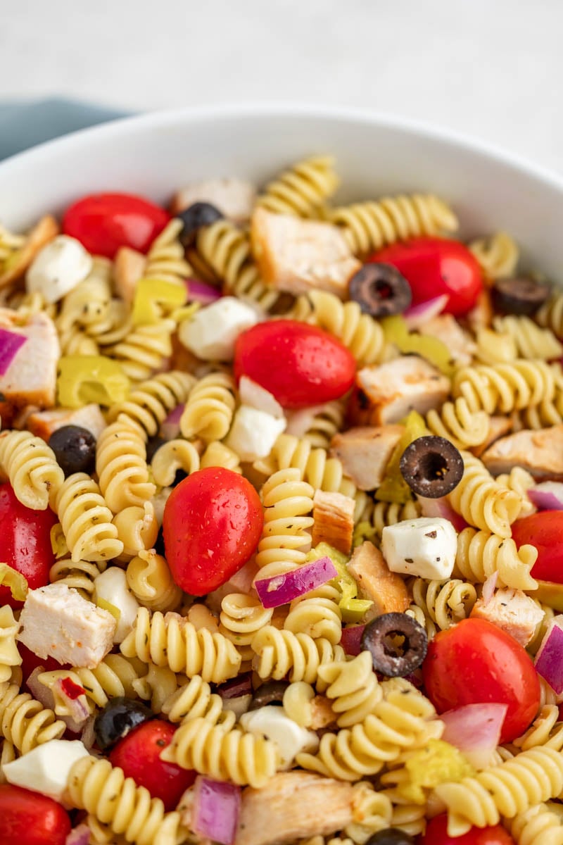 Close up overhead view of chicken pasta salad in a white serving bowl.