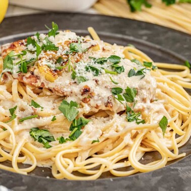 Chicken francese with spaghetti noodles on a dinner plate.