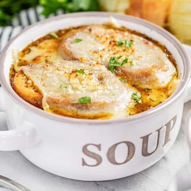 A soup bowl of French onion soup with melted cheese on top.