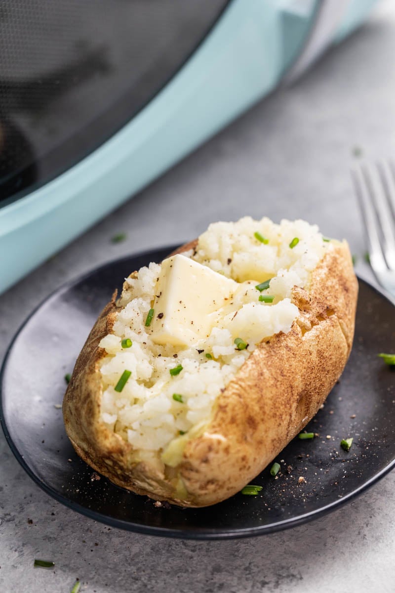 A baked potato cut down the middle with a pat of butter inside.