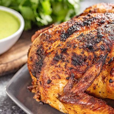 Oven roasted Peruvian chicken on a platter with green dipping sauce