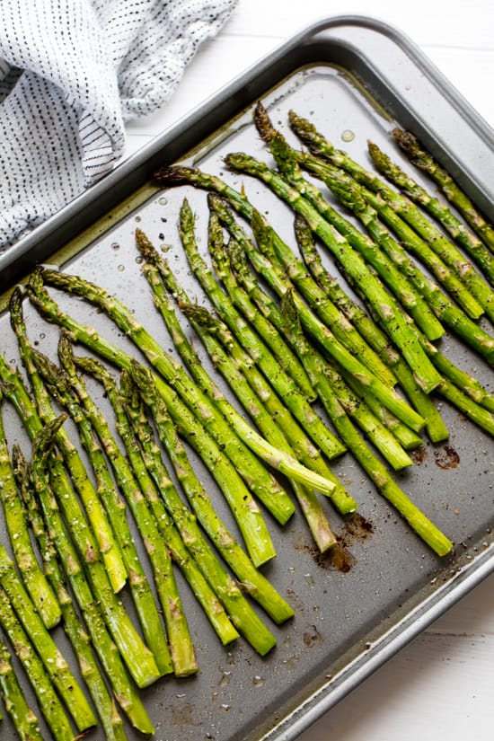 Oven roasted Asparagus lined up on a baking sheet 