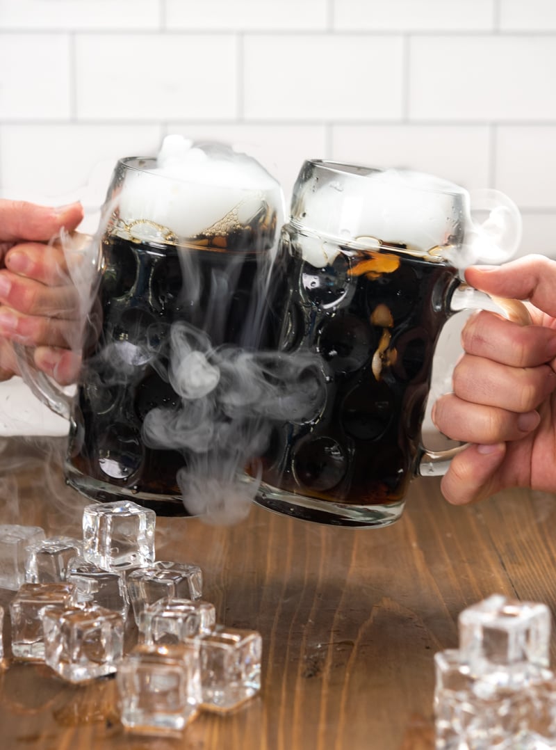 Two people clanking their mugs of root beer together.