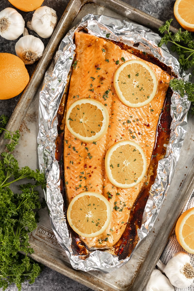 Overhead view of a whole salmon fillet with orange slices on top.