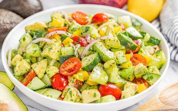 A white serving bowl filled with tomato and avocado salad.