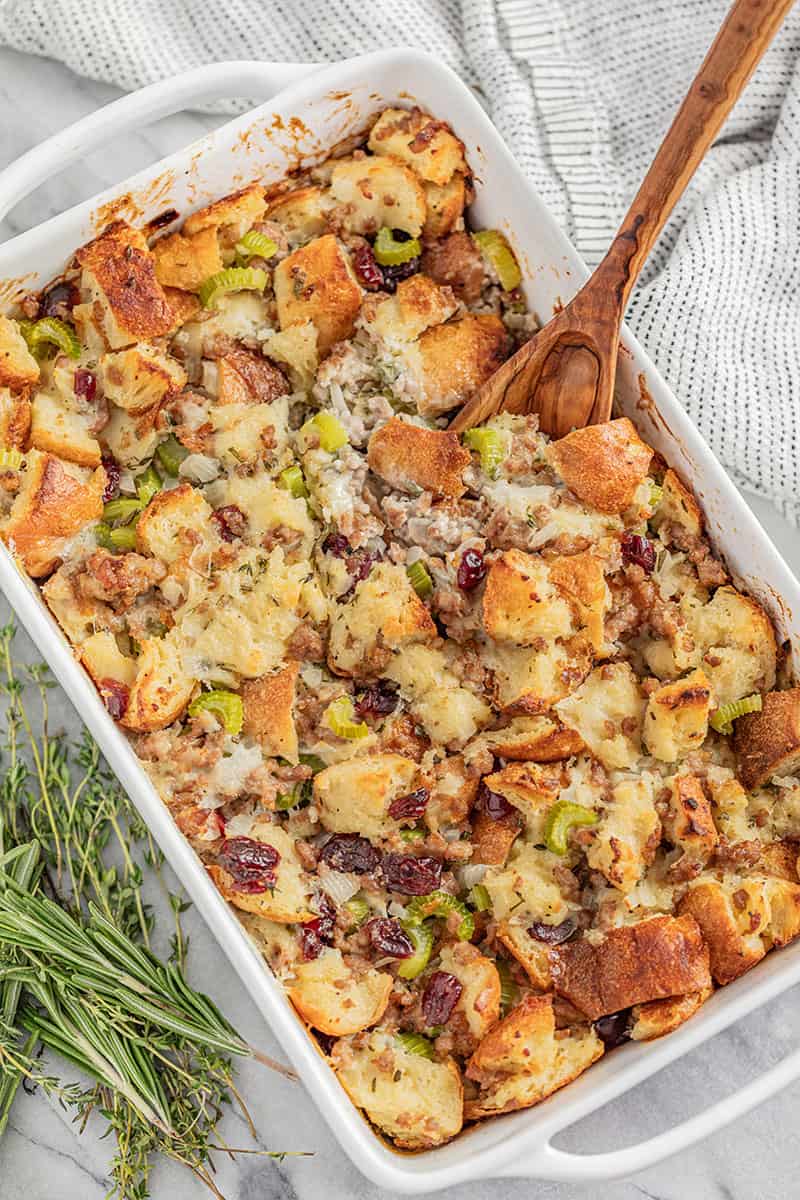 Bird's eye view Sausage Stuffing in a white dish with a wooden spoon in it.