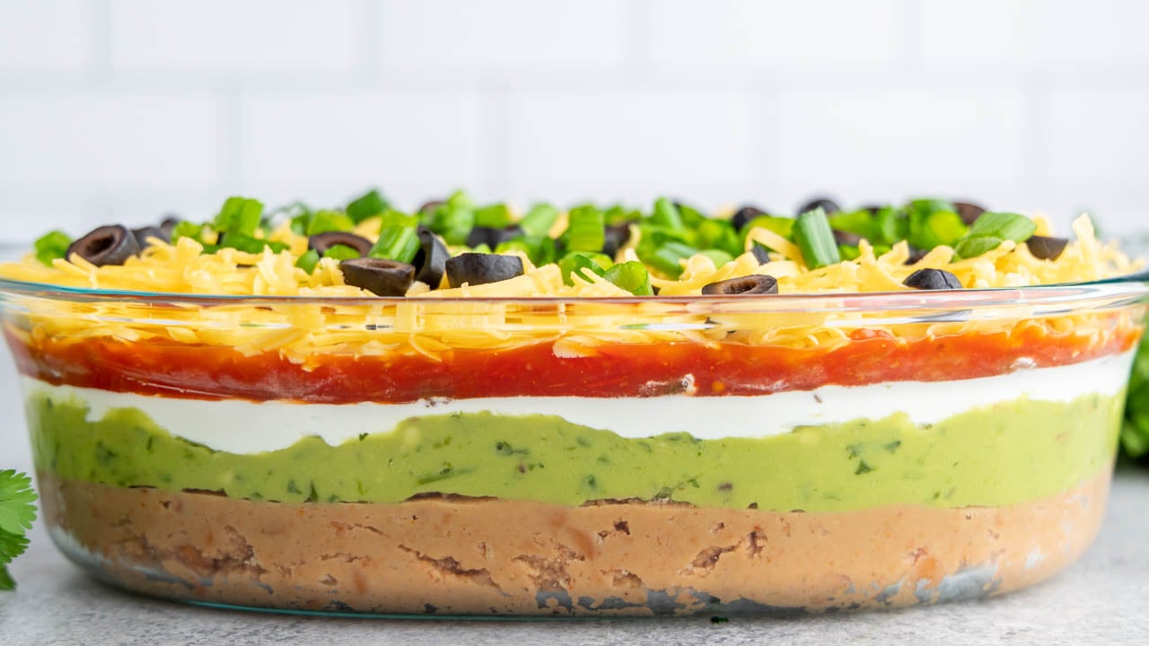 7 layer dip in a glass serving dish.