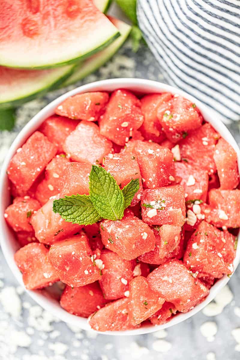 overhead view of watermelon cubed in a bowl with feta cheese, mint, and lemon juice