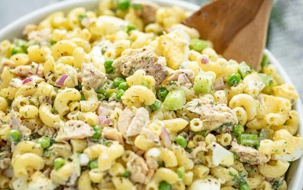 Tuna Macaroni Salad served from a white bowl with a wooden spoon.